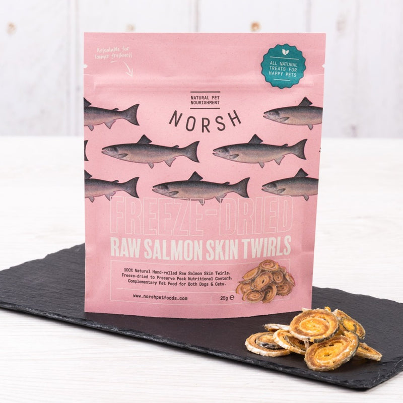 Pink Pouch of Norsh Natural Raw Freeze Dried Salmon Skin Twirls on a slate board